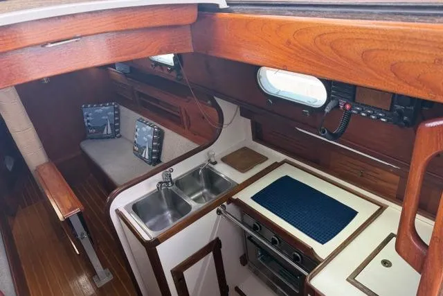 Slide: The Image of Interior of a 1985 Cape Dory Cutter sailboat with wooden cabinetry and compact kitchen. - 10