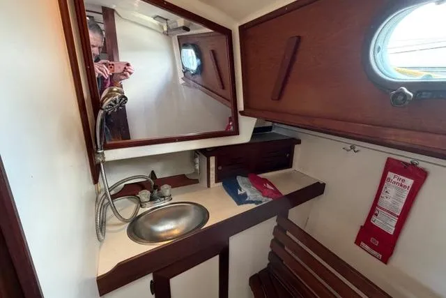 Slide: The Image of 1985 Cape Dory Cutter yacht bathroom with sink, mirror, and fire blanket. - 14