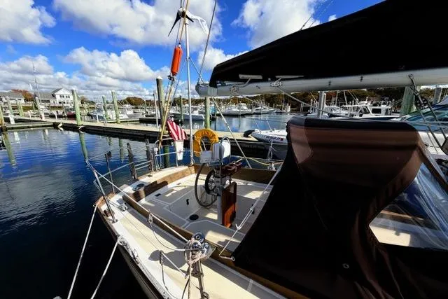 Slide: The Image of 1985 Cape Dory Cutter sailboat docked at a marina under a blue sky. - 17