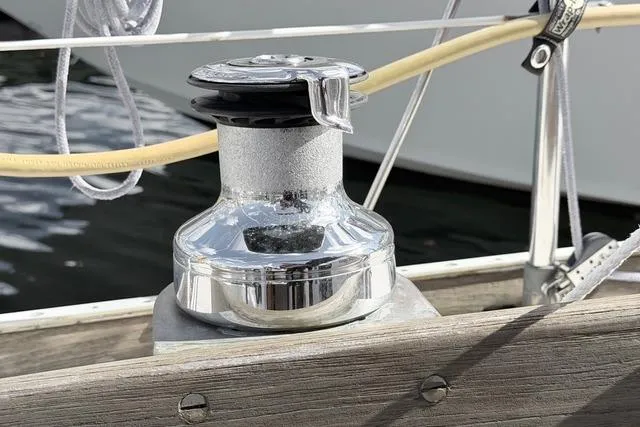 Slide: The Image of Chrome winch on 1985 Cape Dory Cutter sailboat deck, with ropes and wooden railing. - 18
