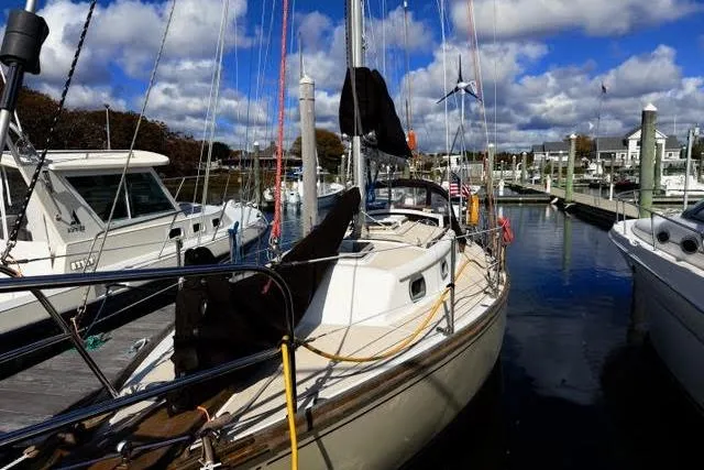 Slide: The Image of 1985 Cape Dory Cutter sailboat docked at a marina under a partly cloudy sky. - 2