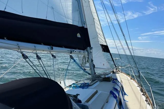 Slide: The Image of 1985 Cape Dory Cutter sailboat navigating open sea under clear blue skies. - 20