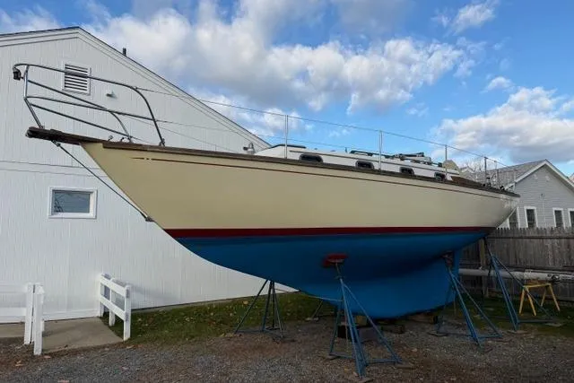 Slide: The Image of 1985 Cape Dory Cutter sailboat on stands, against a cloudy sky backdrop. - 22