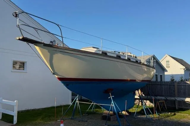 Slide: The Image of 1985 Cape Dory Cutter sailboat on stands, displayed outdoors near buildings. - 23