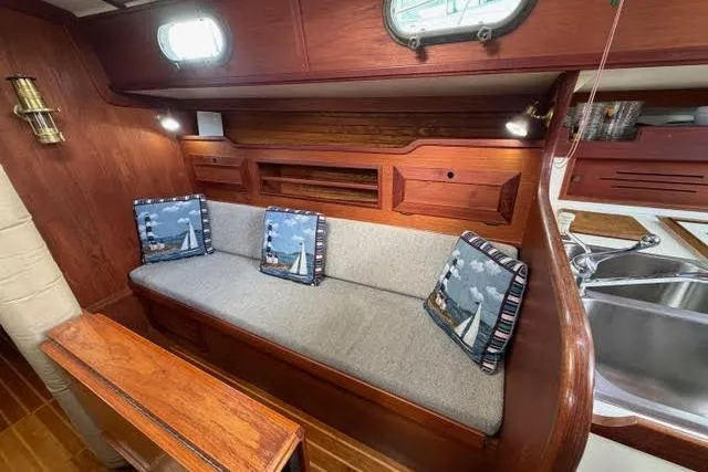 Slide: The Image of 1985 Cape Dory Cutter interior with wooden finish, cushioned seating, and nautical-themed pillows. - 5