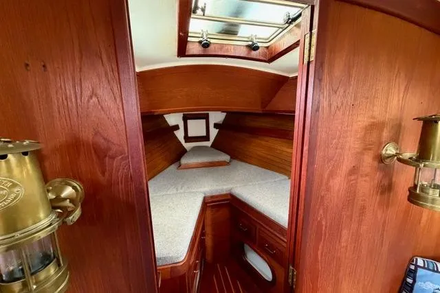 Slide: The Image of 1985 Cape Dory Cutter cabin interior with wooden finish and cozy sleeping area. - 6