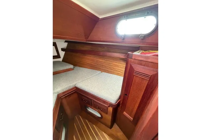 Slide: The Image of 1985 Cape Dory Cutter cabin interior with wooden finish and cushioned seating. - 8