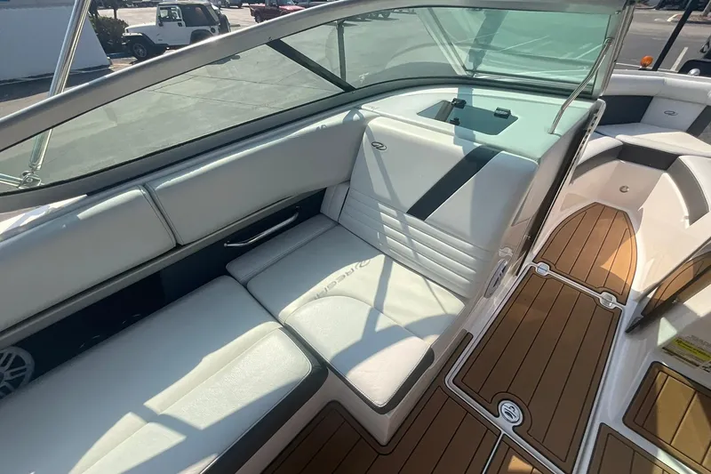 Slide: The Image of 2015 Regal 2100 Bowrider interior with white seating and wood-style flooring. - 13