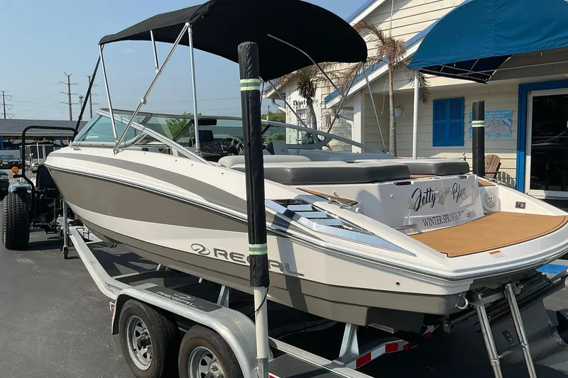 Slide: The Image of 2015 Regal 2100 Bowrider boat on trailer, parked outside a building. - 20