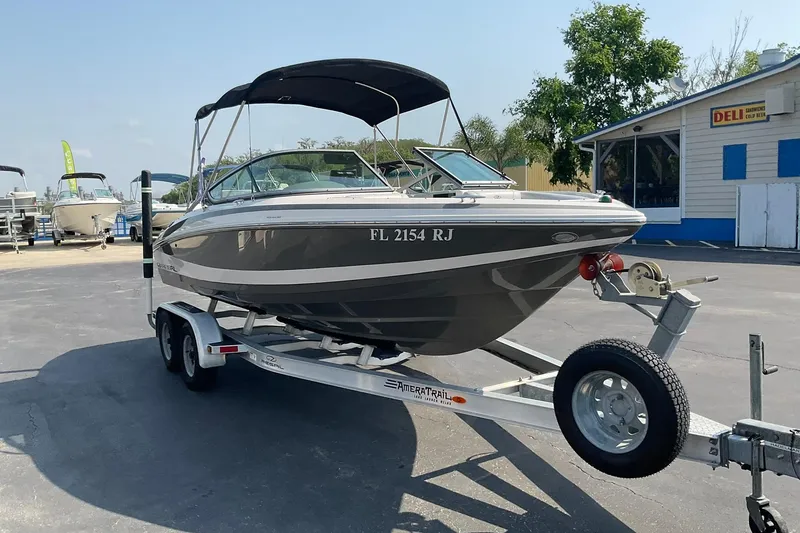 Slide: The Image of 2015 Regal 2100 Bowrider boat on trailer, parked near a deli. - 3