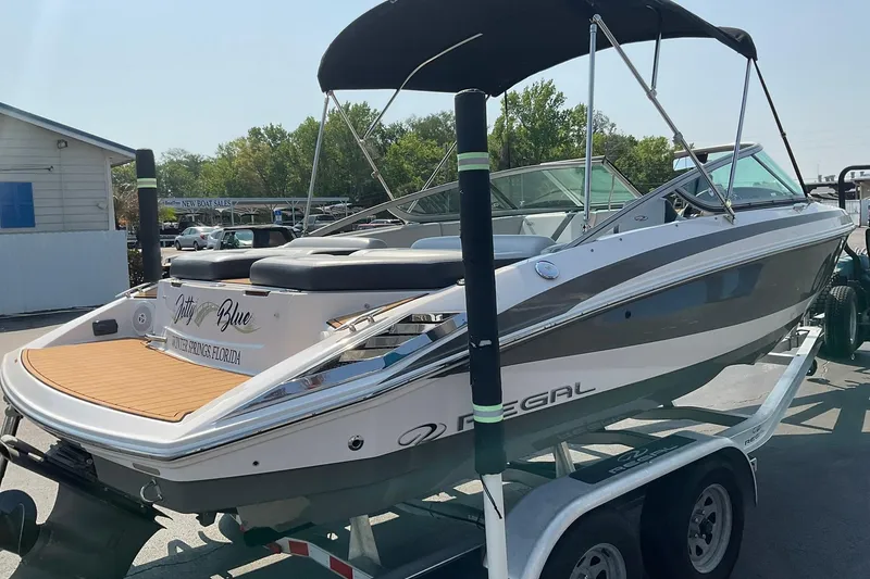 Slide: The Image of 2015 Regal 2100 Bowrider boat on trailer, featuring sleek design and canopy. - 4