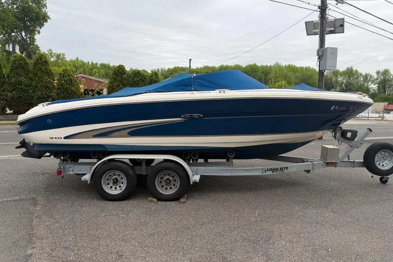 Slide: The Image of 2001 Sea Ray 210 Bow Rider boat on trailer, blue cover, parked roadside. - 2