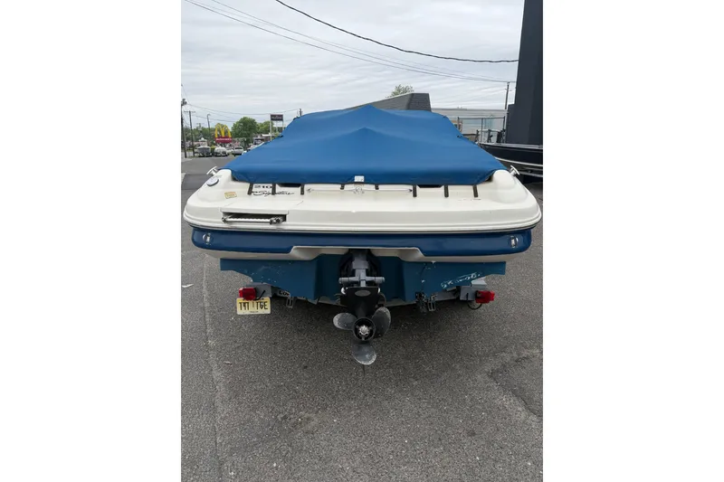 Slide: The Image of 2001 Sea Ray 210 Bow Rider with blue cover, parked on asphalt. - 3