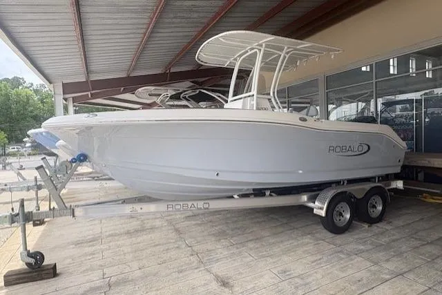 The Image of 2026 Robalo R200 Center Console boat on trailer under a metal roof. - 0