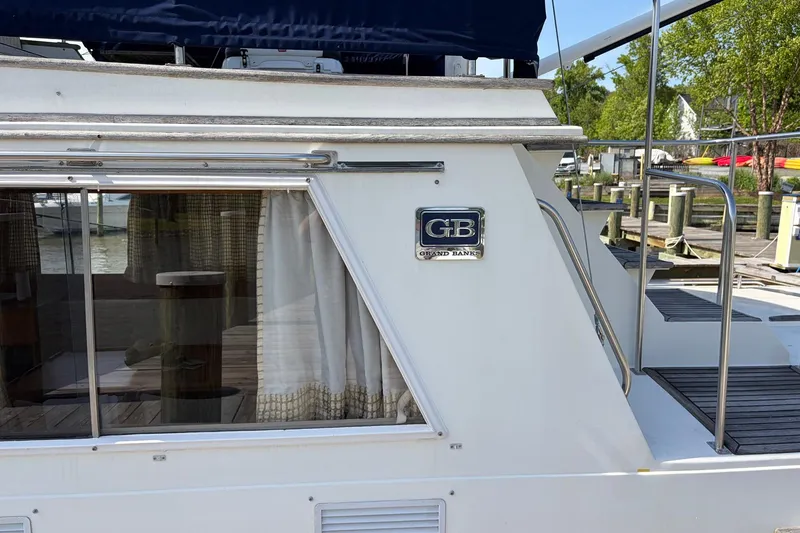 Slide: The Image of 1986 Grand Banks 42 Classic yacht docked, featuring GB logo and window with curtains. - 10