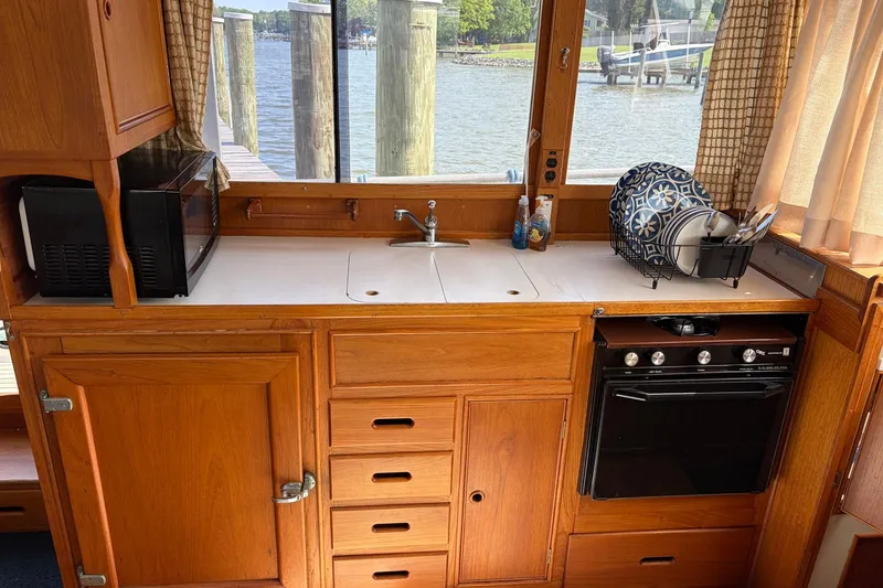 Slide: The Image of 1986 Grand Banks 42 Classic yacht kitchen with wooden cabinetry, sink, and appliances by a window. - 26