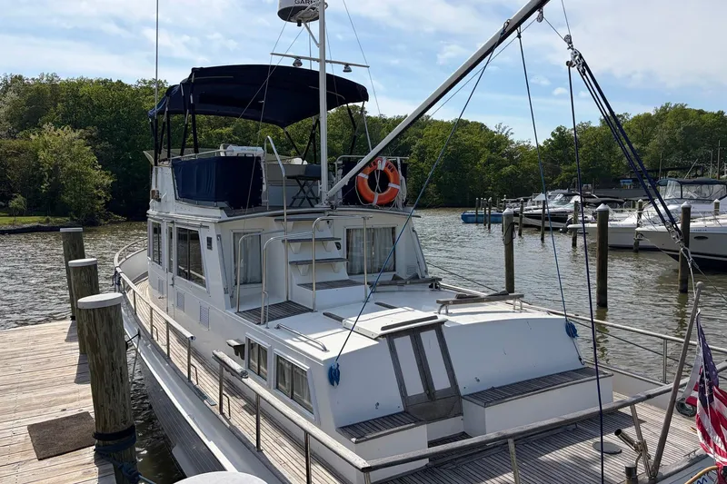 Slide: The Image of 1986 Grand Banks 42 Classic yacht docked at a marina, surrounded by lush greenery. - 43