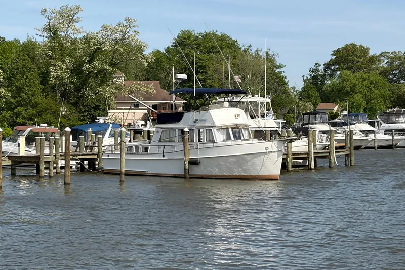 Slide: The Image of 1986 Grand Banks 42 Classic yacht docked at a marina, surrounded by trees and other boats. - 45