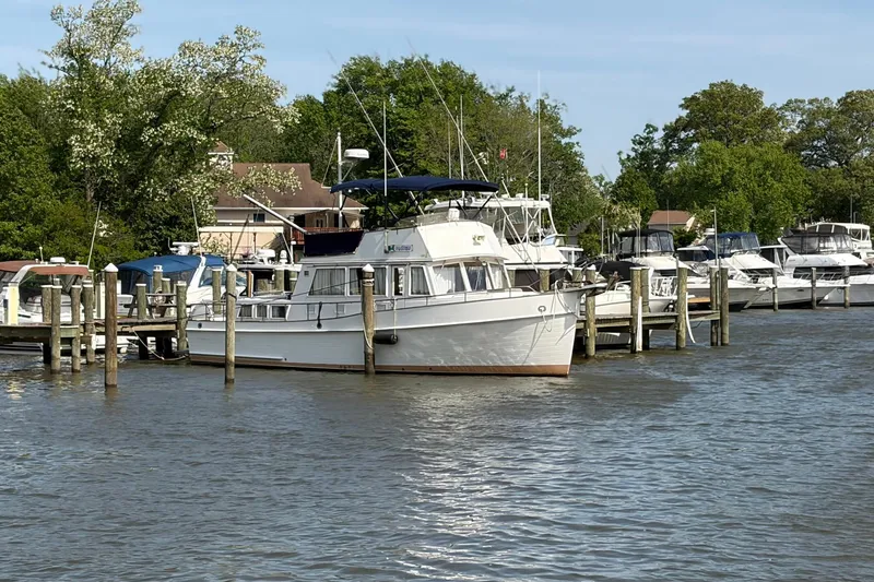 Slide: The Image of 1986 Grand Banks 42 Classic yacht docked at a marina, surrounded by trees and other boats. - 46