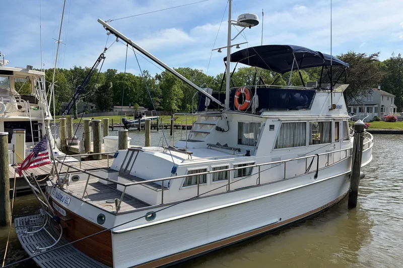 Slide: The Image of 1986 Grand Banks 42 Classic yacht docked at a marina, featuring a blue canopy and American flag. - 5