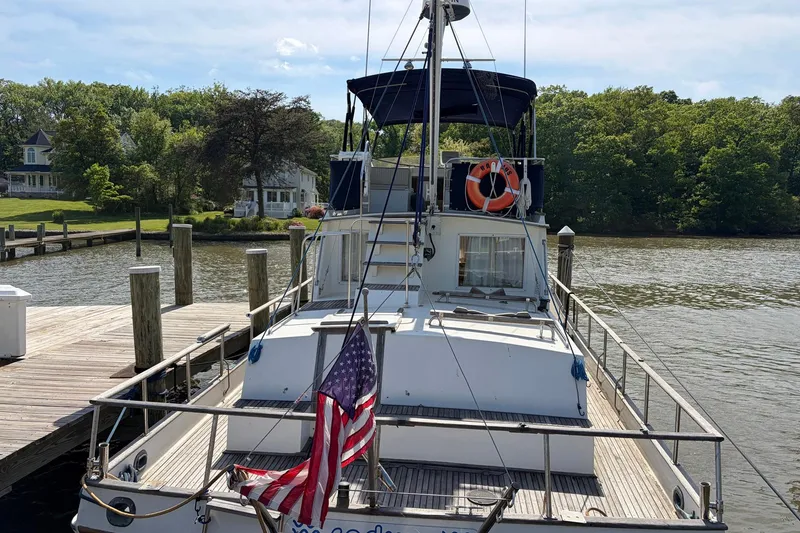 Slide: The Image of 1986 Grand Banks 42 Classic yacht docked by a scenic riverside with lush greenery. - 6
