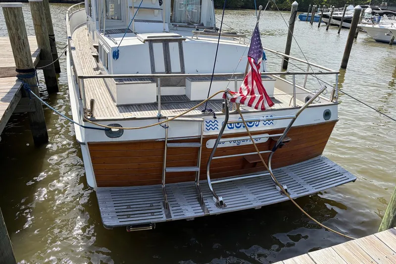 Slide: The Image of 1986 Grand Banks 42 Classic yacht docked, featuring wooden accents and American flag. - 7