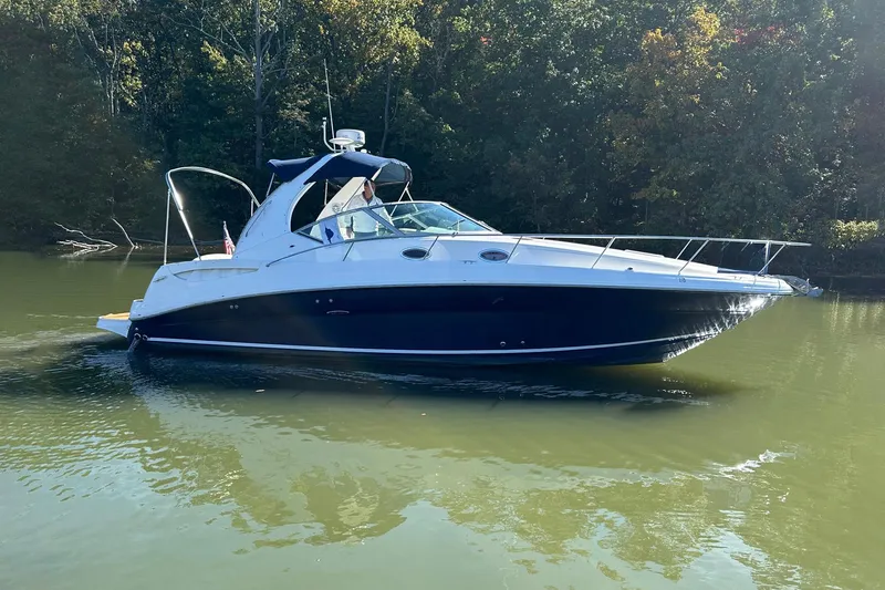 Slide: The Image of 2005 Sea Ray 320 Sundancer boat cruising on a calm lake with forest backdrop. - 1