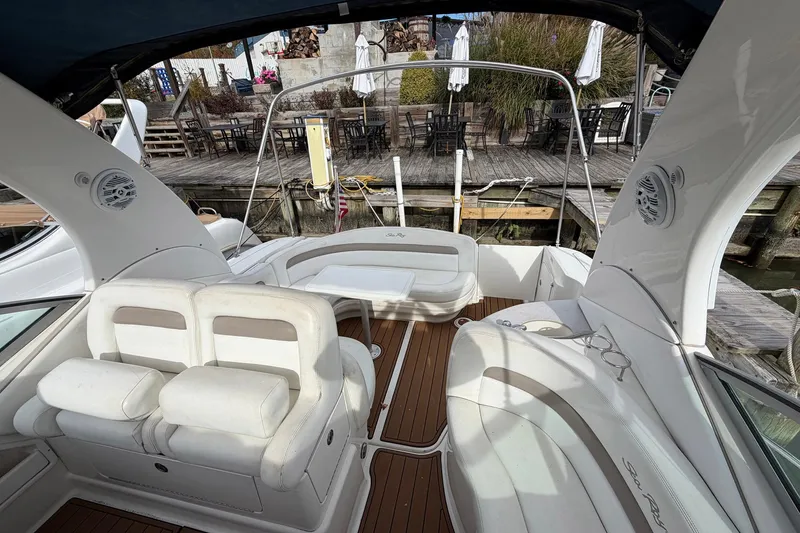 Slide: The Image of 2005 Sea Ray 320 Sundancer boat interior with white seating and wooden deck. - 10