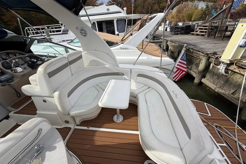 Slide: The Image of 2005 Sea Ray 320 Sundancer boat with white seating and wooden deck at a marina. - 12