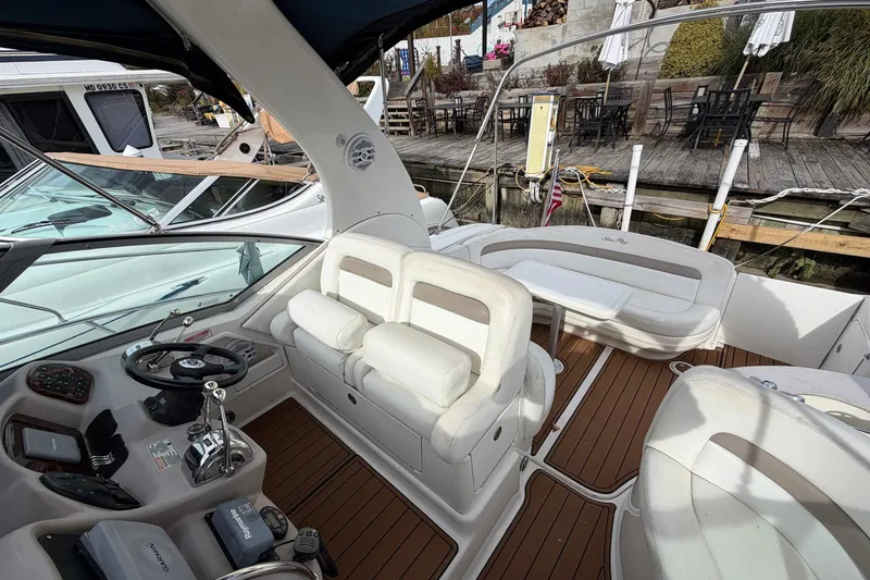Slide: The Image of 2005 Sea Ray 320 Sundancer boat interior with white seating and wooden deck. - 9