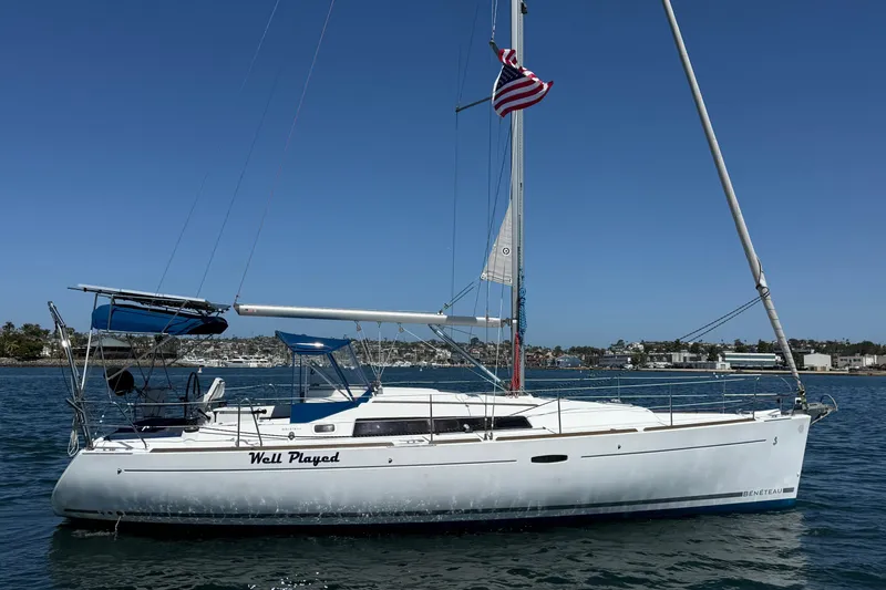 The Image of 2012 Beneteau Oceanis 37 sailboat on water, clear sky, American flag flying. - 0