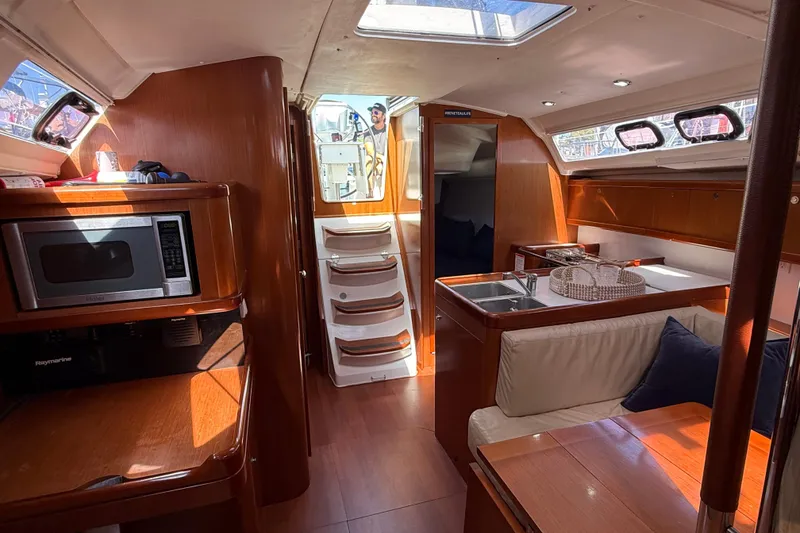 Slide: The Image of Interior of 2012 Beneteau Oceanis 37 yacht, featuring a cozy kitchen and seating area. - 17