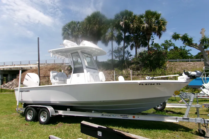 The Image of 2023 Sportsman Masters 247 Bay Boat on trailer, parked outdoors with palm trees. - 1