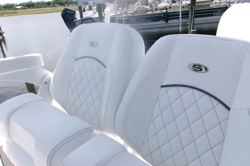 Slide: The Image of 2023 Sportsman Masters 247 Bay Boat seats with diamond stitching, docked by the water. - 15