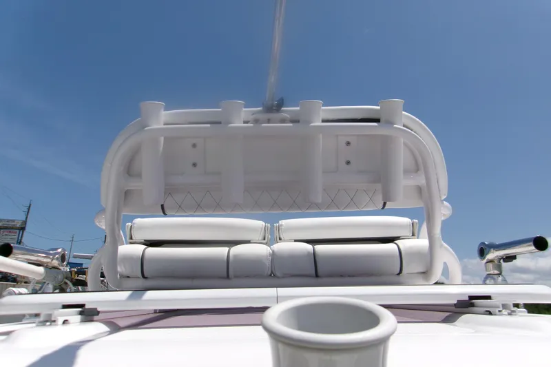 Slide: The Image of 2023 Sportsman Masters 247 Bay Boat interior with rod holders and seating, under clear blue sky. - 7