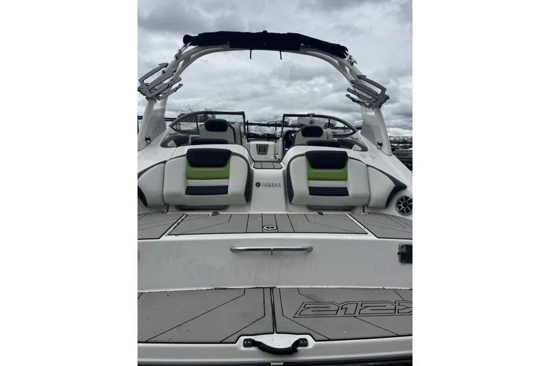 Slide: The Image of 2021 Yamaha Boats 212XD with sleek seating and modern design under cloudy skies. - 2
