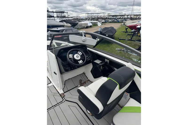 Slide: The Image of 2021 Yamaha Boats 212XD cockpit with steering wheel and seating, parked outdoors. - 4