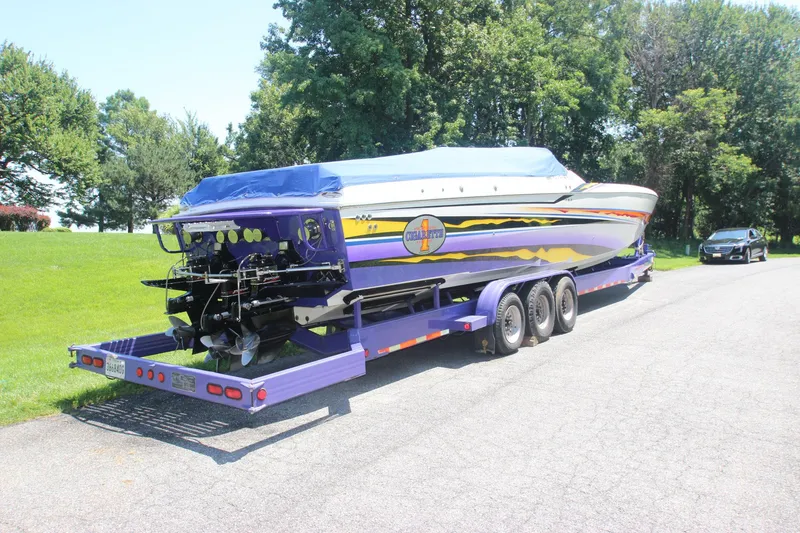 Slide: The Image of 2001 Cigarette 46 Rough Rider boat on trailer, parked on road with green trees in background. - 34