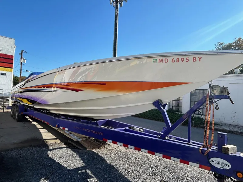 Slide: The Image of 2001 Cigarette 46 Rough Rider boat on trailer, vibrant orange and purple design, clear blue sky. - 37