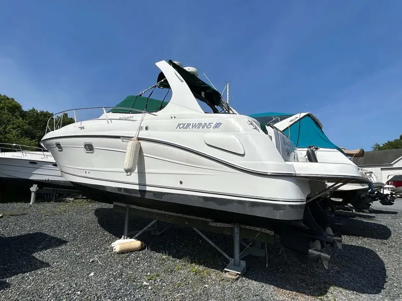 The Image of 2001 Four Winns 328 Vista boat on stands, white hull, green canopy, sunny day. - 0