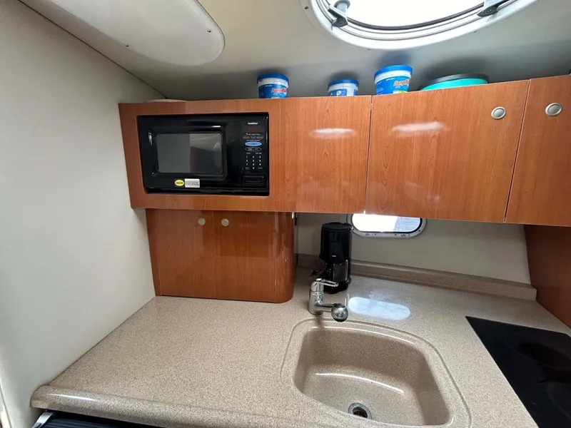 Slide: The Image of 2001 Four Winns 328 Vista boat kitchen with microwave, sink, and wooden cabinets. - 11