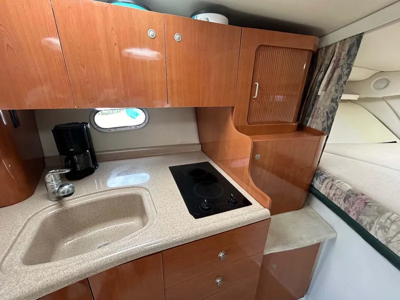 Slide: The Image of 2001 Four Winns 328 Vista boat kitchen with sink, stove, and wooden cabinets. - 12