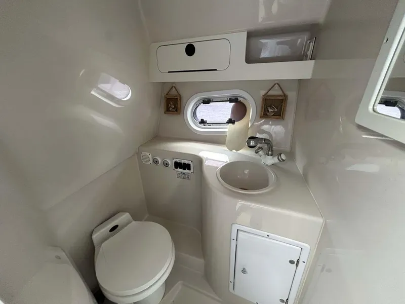 Slide: The Image of 2001 Four Winns 328 Vista boat bathroom with sink, toilet, and porthole window. - 16