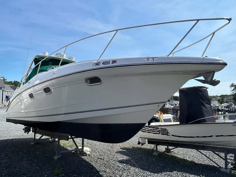 Slide: The Image of 2001 Four Winns 328 Vista boat on display, elevated on stands, under clear blue sky. - 2