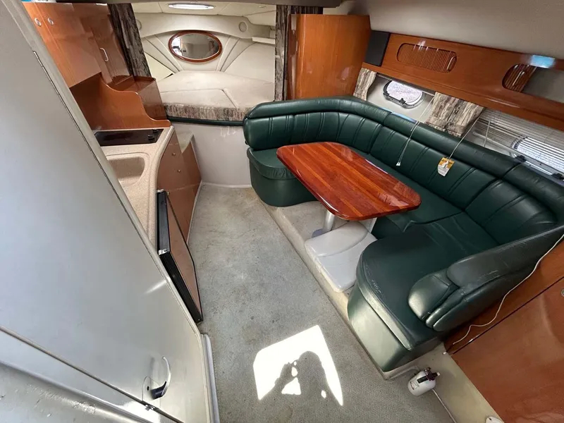 Slide: The Image of 2001 Four Winns 328 Vista interior with green seating, wooden table, and compact kitchen area. - 5