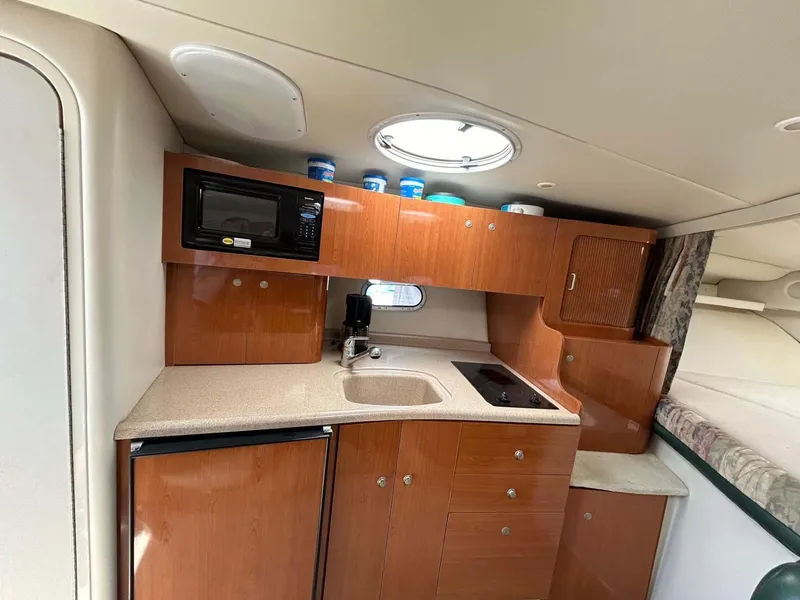 Slide: The Image of 2001 Four Winns 328 Vista boat kitchen with wood cabinets, sink, microwave, and compact fridge. - 9