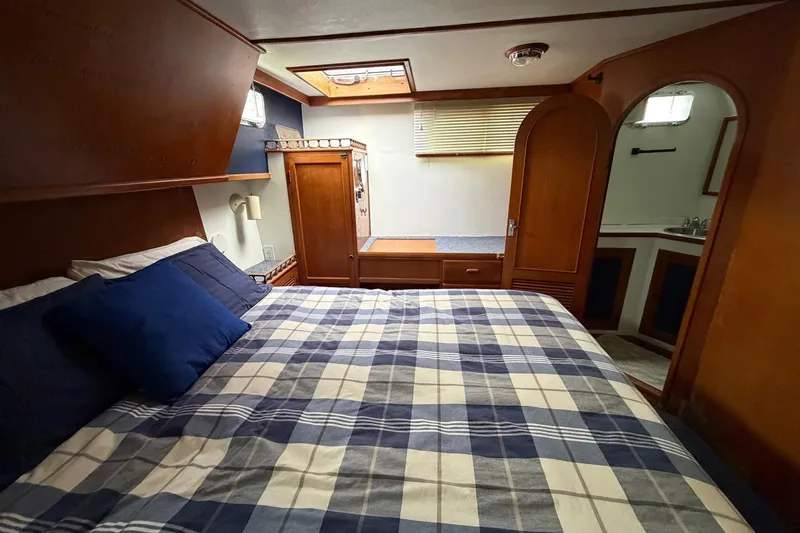 Slide: The Image of Cozy bedroom in 1984 Golden Star 38 Trawler with plaid bedding and wooden cabinetry. - 39