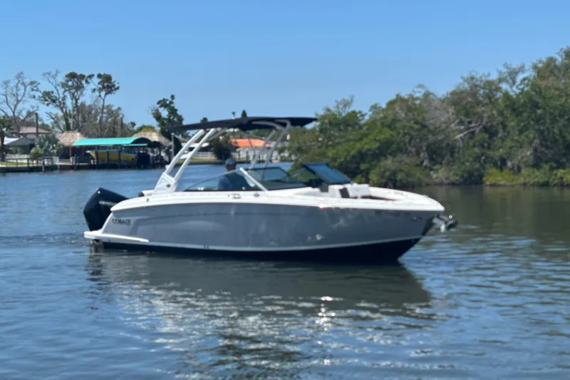 The Image of 2022 Cobalt R6 Outboard boat cruising on a calm river with lush greenery. - 0