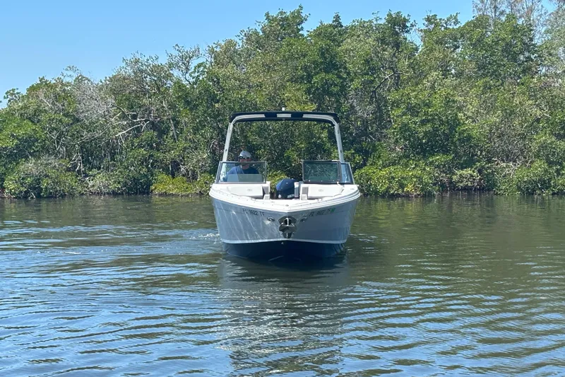 Slide: The Image of 2022 Cobalt R6 Outboard boat cruising on a calm river with lush greenery. - 2