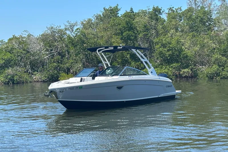 Slide: The Image of 2022 Cobalt R6 Outboard boat cruising on a calm river with lush greenery. - 3